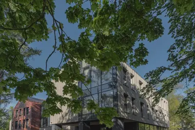 an office building with a glass facade with trees at LAJOS Hotel in Birštonas