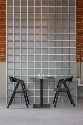 a table and two stools in front of a brick wall at LAJOS Hotel in Birštonas