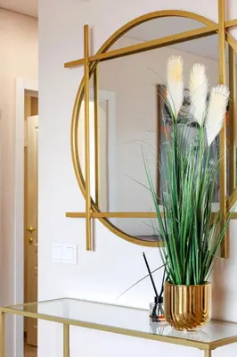 a glass table with a gold mirror and a plant at Modernus butas prie EŽERO in Vilnius
