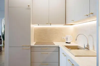 a kitchen with white cabinets and a sink at Modernus butas prie EŽERO in Vilnius