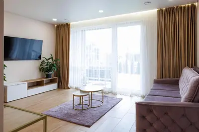 a living room with a couch and a tv at Modernus butas prie EŽERO in Vilnius