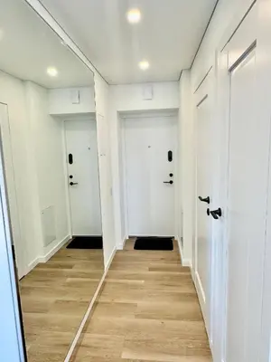 an empty hallway with white doors and wood floors at Draugystės apartamentai II in Šiauliai