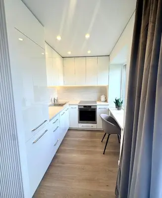 a kitchen with white cabinets and a table and a chair at Draugystės apartamentai II in Šiauliai