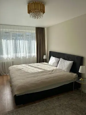 a bedroom with a large bed with a chandelier at NESTAa in Druskininkai