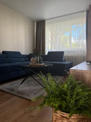 a living room with a blue couch and a table at NESTAa in Druskininkai