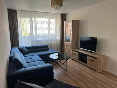 a living room with a blue couch and a television at NESTAa in Druskininkai