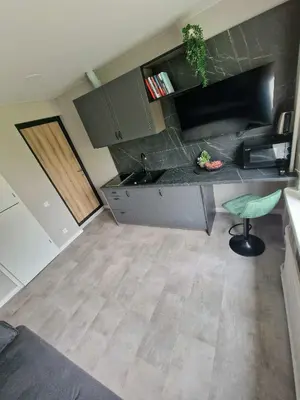 a kitchen with a counter and a green stool at Trumpalaikė butų nuoma Kaune prie Klinikų SELF CHECK-IN in Kaunas