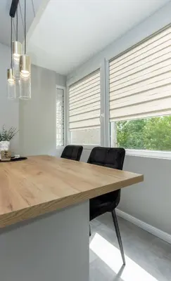 a kitchen with a wooden table and two windows with blinds at Trumpalaikė butų nuoma Kaune prie Klinikų SELF CHECK-IN in Kaunas