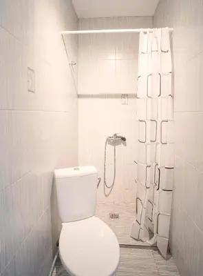 a white bathroom with a toilet and a shower at Compact and Comfy Apartment on the Greenhill in Kaunas