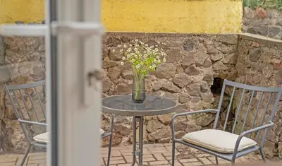 a table and chairs with a vase of flowers on it at Compact and Comfy Apartment on the Greenhill in Kaunas