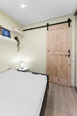 a bedroom with a large bed and a wooden door at Ramybes Oaze, Nauji stylingi apartamentai in Panevėžys