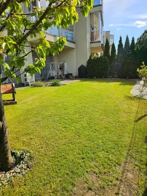 a green yard with a building and a tree at 3 rooms 3 beds apartment with garden in Kaunas