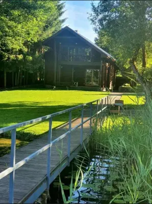 a wooden bridge leading to a cabin with a pond at Atostogų namelis ant ežero kranto in Juočionys