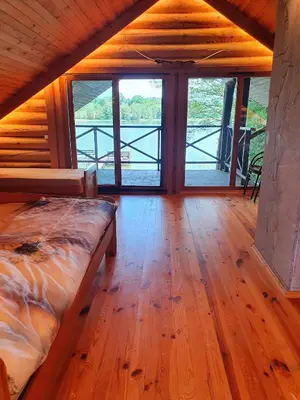 a room with a bed and a view of the water at Atostogų namelis ant ežero kranto in Juočionys