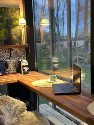 a laptop sitting on a wooden table next to a window at Vilnius river house in Dusinėnai