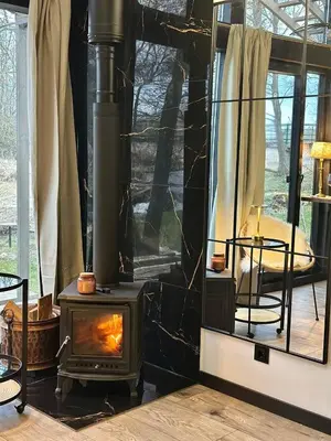 a fireplace in a living room with a stove at Vilnius river house in Dusinėnai