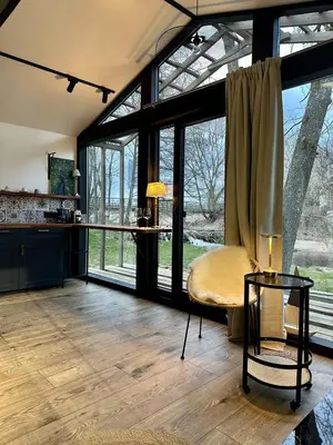 a living room with a couch and a table and windows at Vilnius river house in Dusinėnai