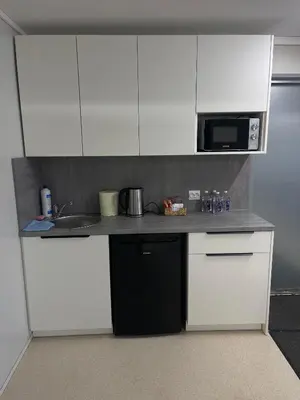 a kitchen with white cabinets and a sink and a microwave at Pabrades Apartamentai in Pabradė