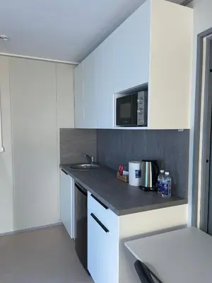 a kitchen with white cabinets and a sink and a microwave at Pabrades Apartamentai in Pabradė