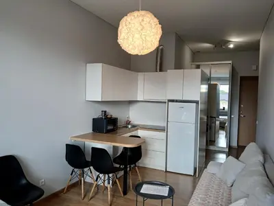 a kitchen with white cabinets and a table and chairs at Studija Kauno centre in Kaunas
