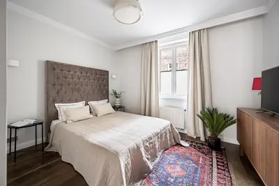 a white bedroom with a large bed and a tv at Super Central Studio in Vilnius