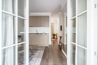 a kitchen with white cabinets and a hallway with windows at Super Central Studio in Vilnius