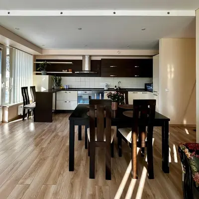 a kitchen and dining room with a black table and chairs at Sunny Lotus Apartamentai in Druskininkai