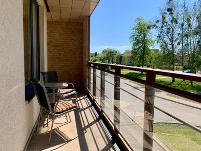 a balcony with a chair and a laptop on it at Sunny Lotus Apartamentai in Druskininkai