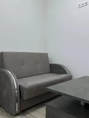 a gray couch sitting in a living room next to a table at Užupio Apartamentai Nemokamas parkingas 2 in Vilnius