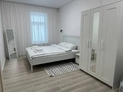 a white bedroom with a bed and a mirror at Užupio Apartamentai Nemokamas parkingas 2 in Vilnius