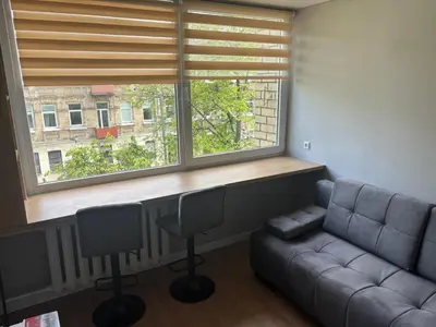 a living room with a couch and a large window at RR Apartments in Algirdo street in Vilnius