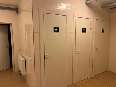 three doors in a bathroom with signs on them at Linkmenų sporto ir rekreacijos centras in Linkmenys