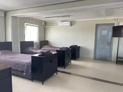 a room with two beds with purple sheets and tables at Pabrades Apartamentai in Pabradė