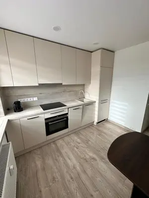 a kitchen with white cabinets and a stove top oven at Lauros Apartamentai in Kupiškis