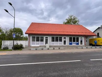 a building with an orange roof on the side of a street at Menulio Misko Nights in Vilkija