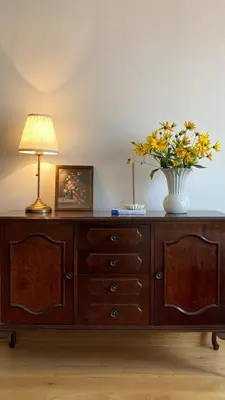 a wooden dresser with a vase of yellow flowers on it at Kalinovs Stay Apartment in Adutiškis