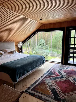 a bedroom with a bed and a large window at Secluded private villa in the middle of the woods in Margionys