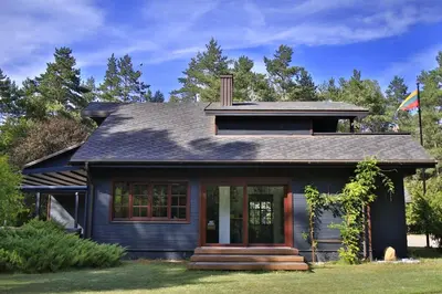 a black house with a flag in front of it at Secluded private villa in the middle of the woods in Margionys