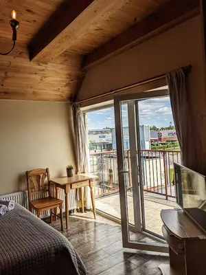 a bedroom with a bed and a table and a balcony at Guest House Kamara in Panevėžys