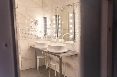 a white bathroom with two sinks and two stools at Hostel K3a in Vilnius