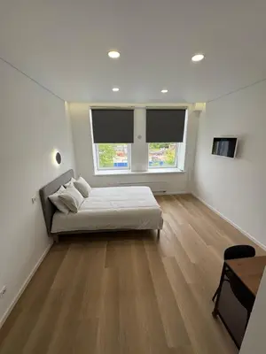 a bedroom with a bed and a desk and two windows at 5 New Airport Apartment in VNO
