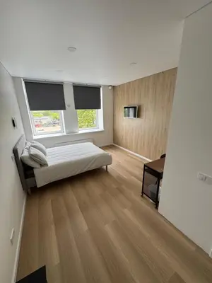 a bedroom with a bed and a desk and two windows at 6 New Airport Apartment in VNO