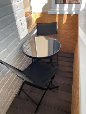 a glass table and two chairs on a balcony at Centro apartamentai in Biržai