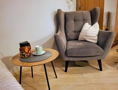 a chair and a coffee table with a cup of coffee at Cozy Studio in Vilnius Old Town in Vilnius
