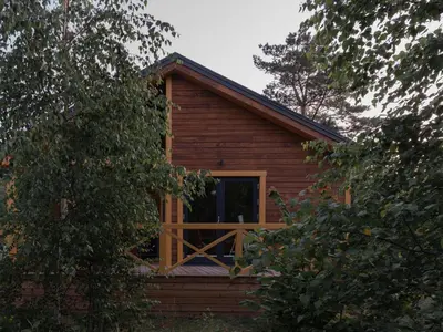 a log cabin with a large window and trees at Getlost cabins in Valanciunai