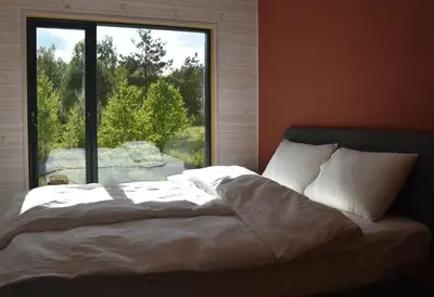 a bed in a room with a large window at Getlost cabins in Valanciunai