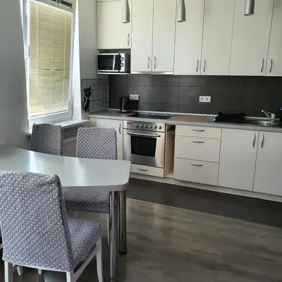 a kitchen with white cabinets and a table and chairs at Apartment Beauty in Vilnius