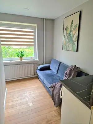 a living room with a blue couch and a window at Trumpalaikė butų nuoma Kaune prie Klinikų MINIUKAS SELF CHECK-IN in Kaunas
