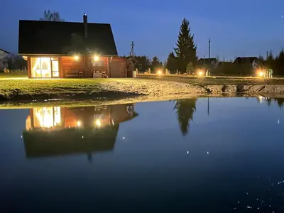 a house with a reflection in a pond at night at 12 Bijūnų in Joniškis