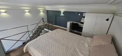 a bedroom with a bed and a staircase with a desk at Telegrafas25-modern apartment in the center of Kaunas in Kaunas